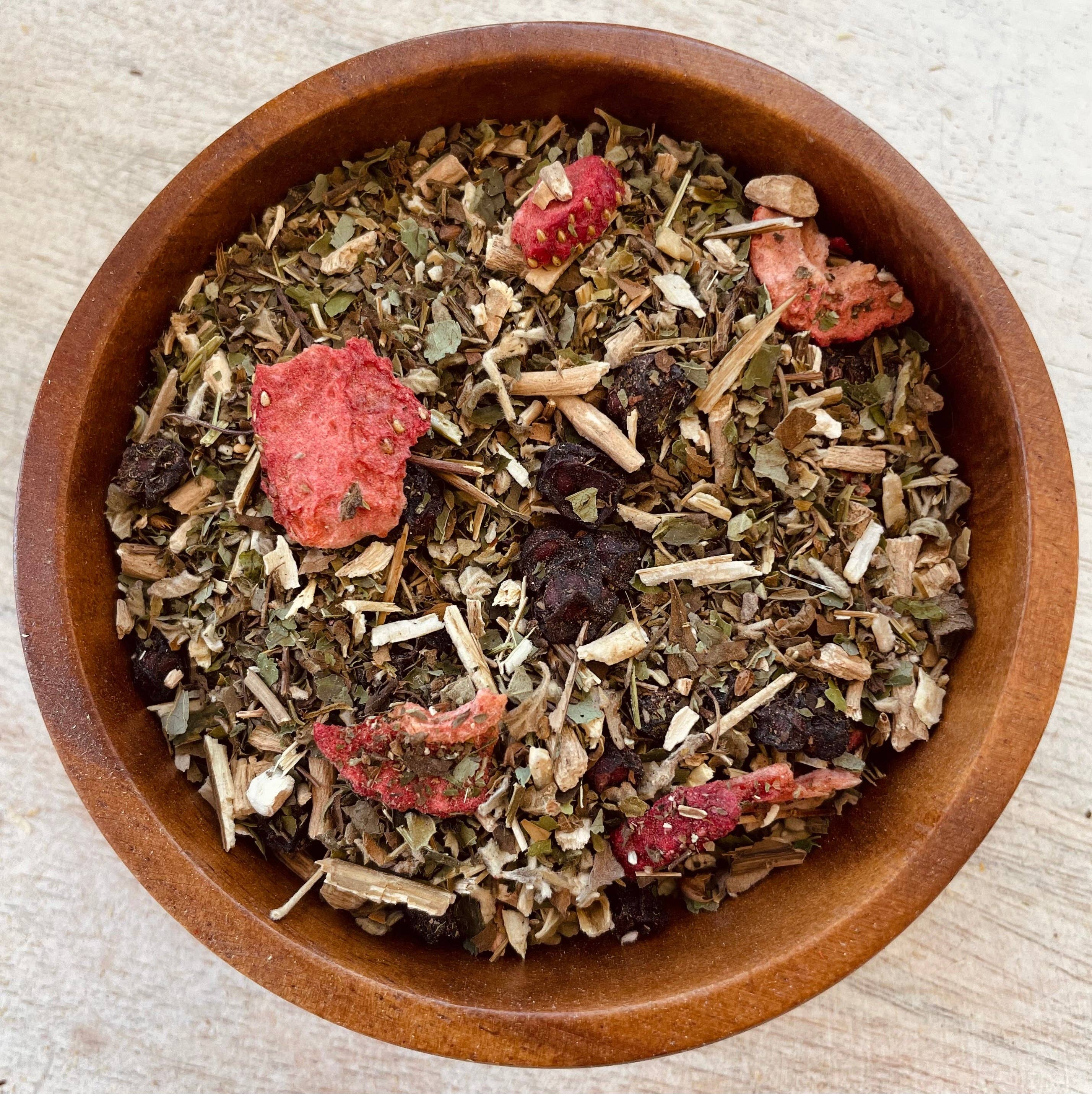 Wooden bowl filled with a mix of dried herbs and berries on a light background