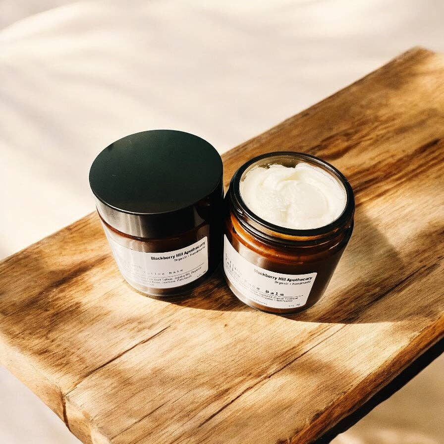 Two jars of cream on a wooden board with a neutral background