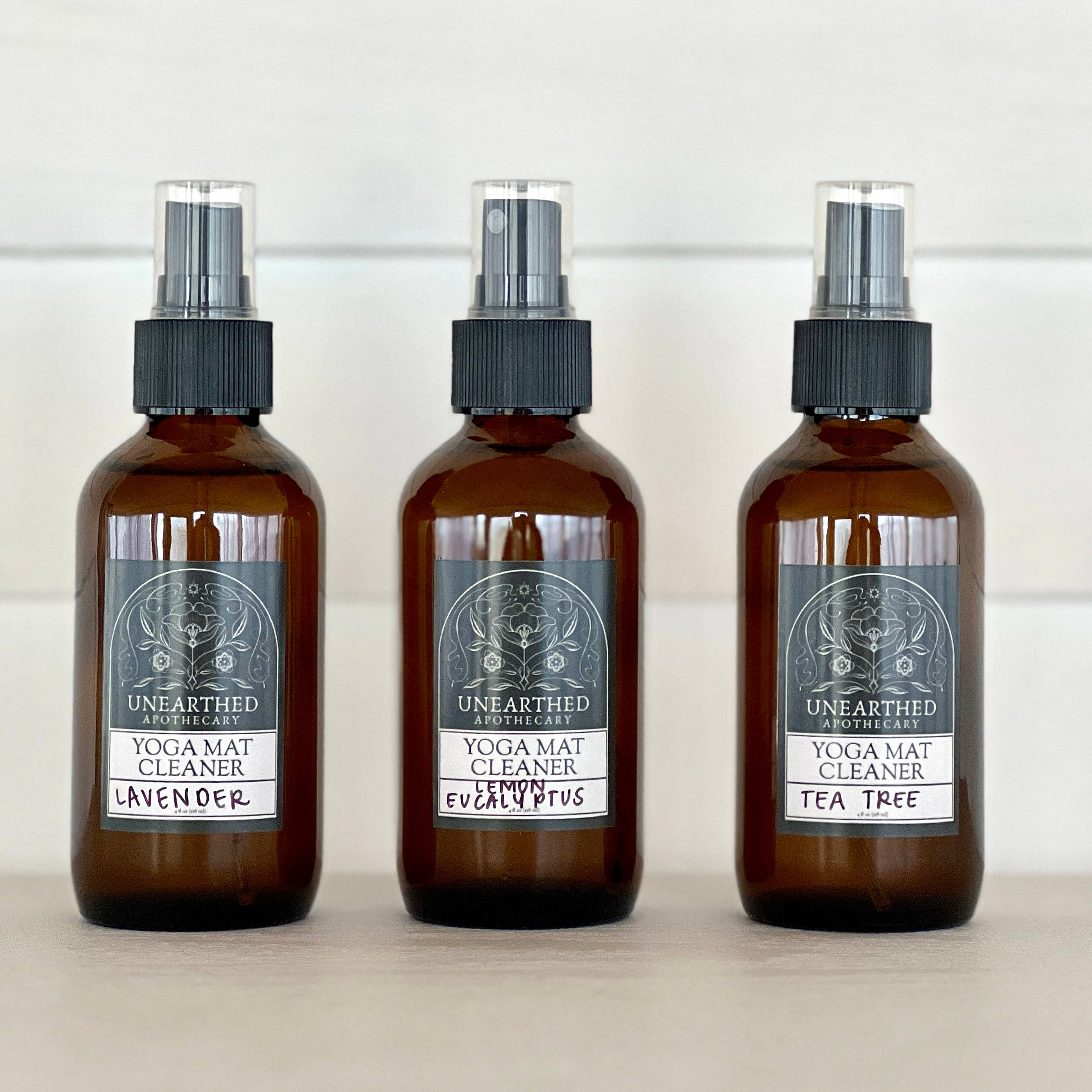Three bottles of Unearthed & Ancestral Yoga Mat Cleaner on a white background