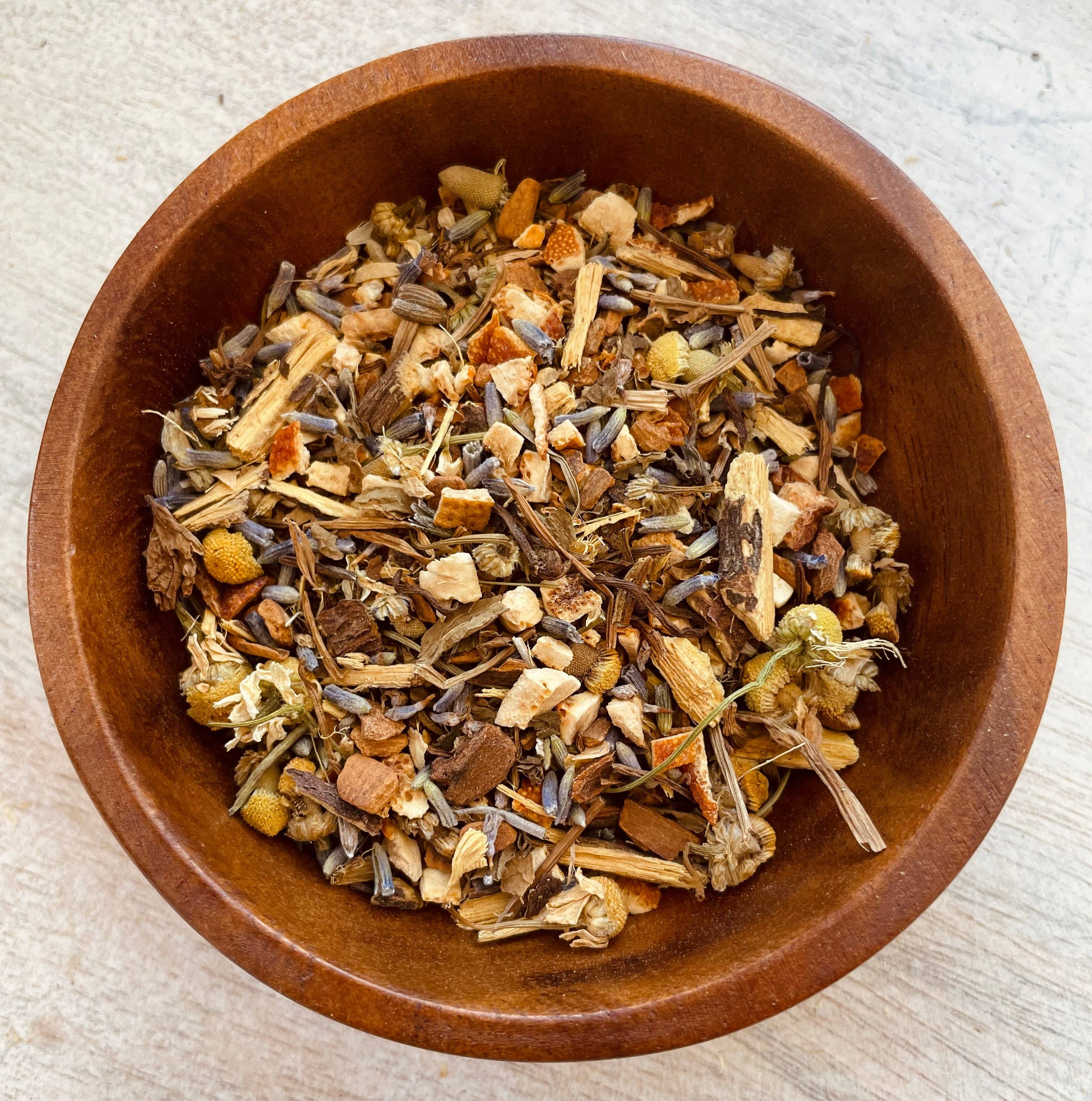 Wooden bowl filled with a mix of dried herbs and spices on a light fabric background