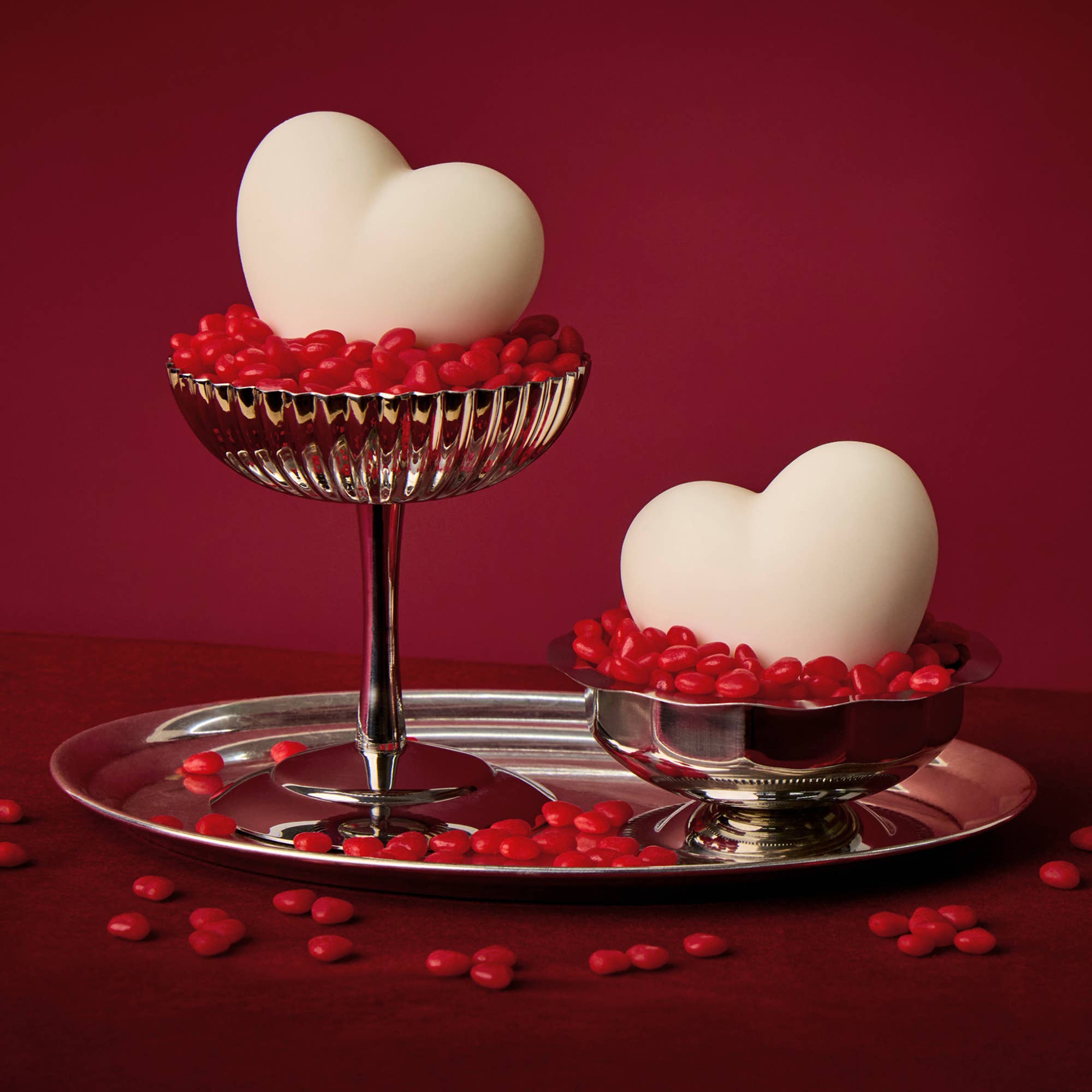 Two white eggs on a silver stand with red decorative stones on a red background