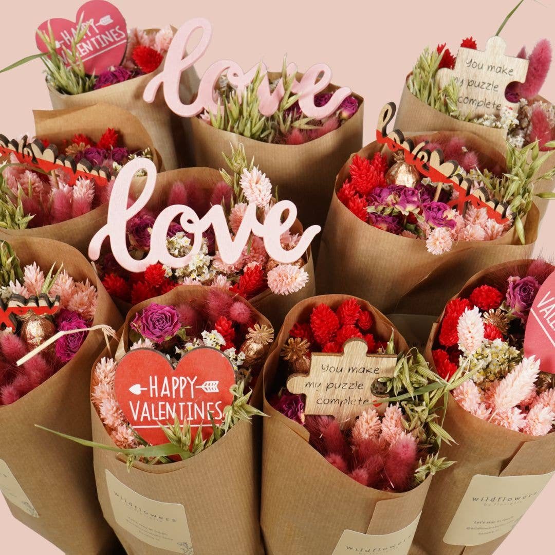 Valentine's Day flower bouquets with 'love' and heart-shaped cards on a pink background