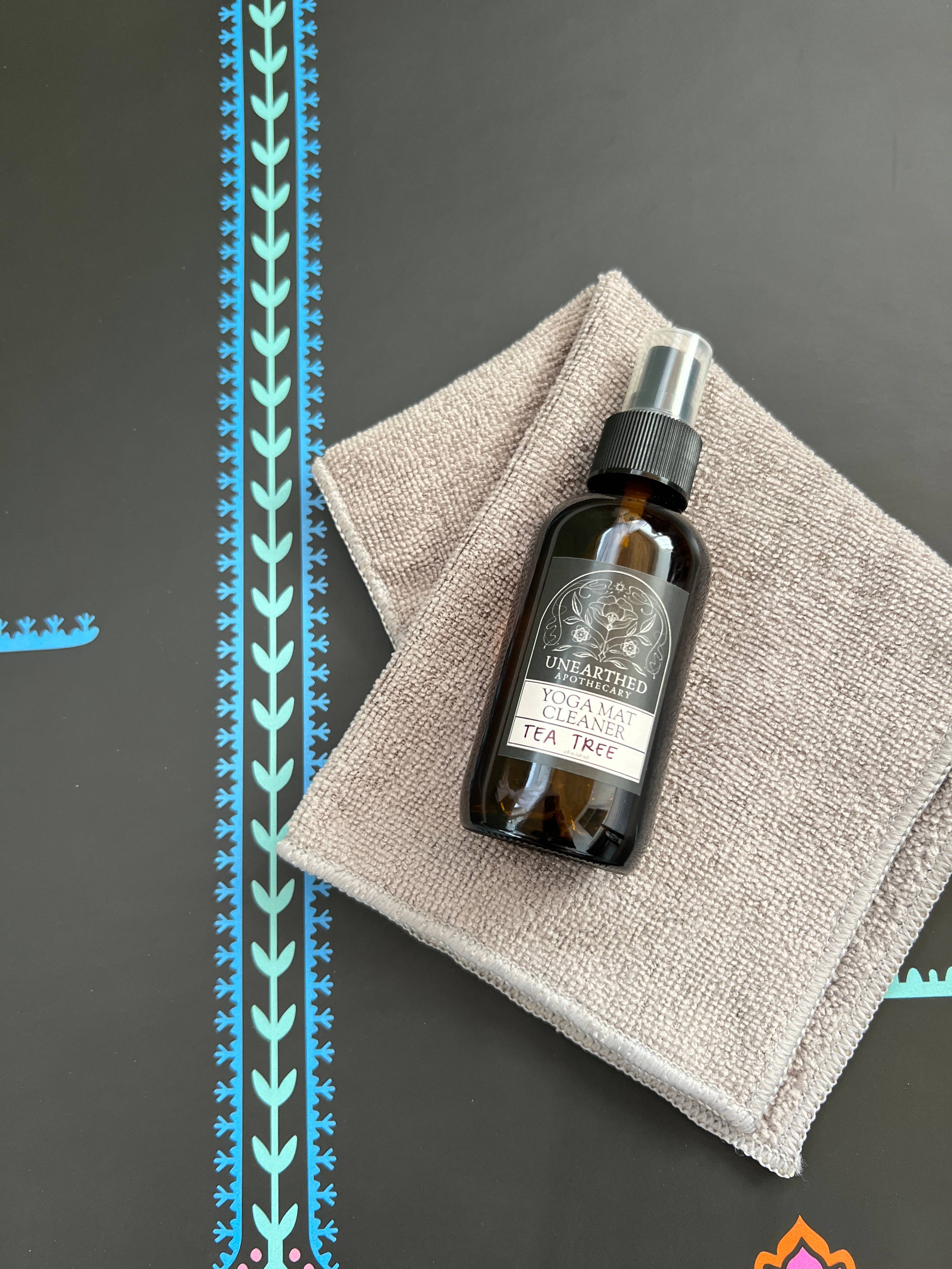 Bottle of tea tree oil on a textured surface with decorative elements.