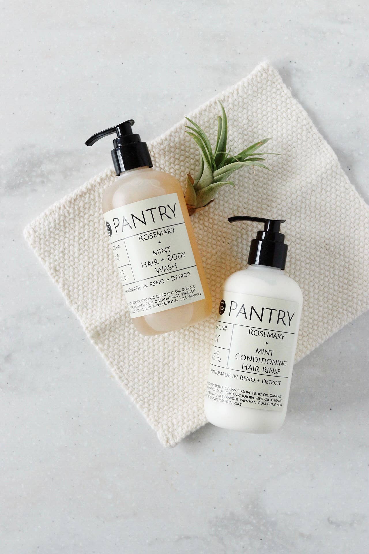Two bottles of Pantry hair care products on a textured surface