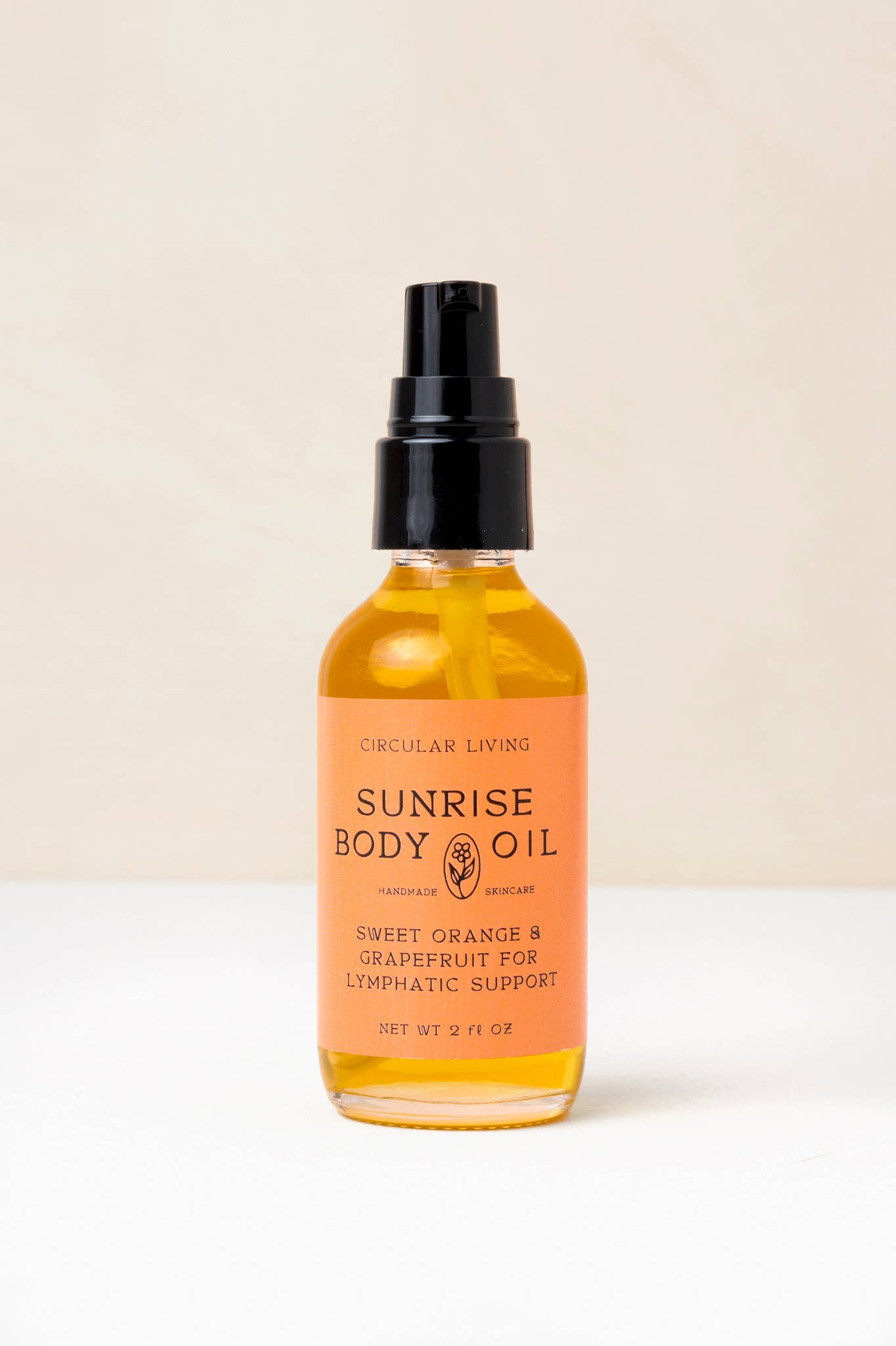 Bottle of Sunrise Body Oil with a black spray nozzle on a beige background